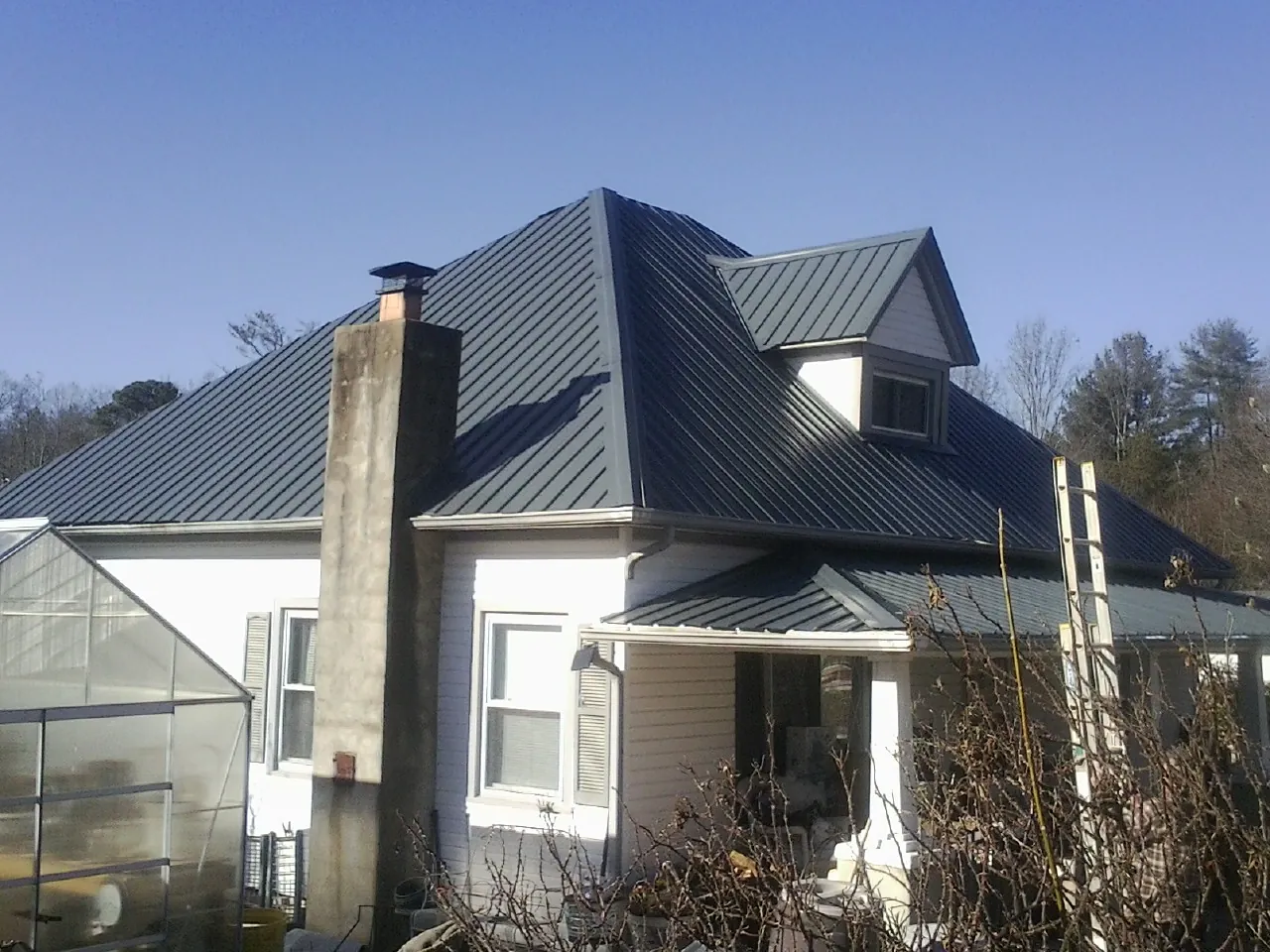 Dark blue standing seam metal roof on a white farmhouse with dormer — Slate & Tile Roof Repair by Roofing Brothers in Old Orchard Beach
