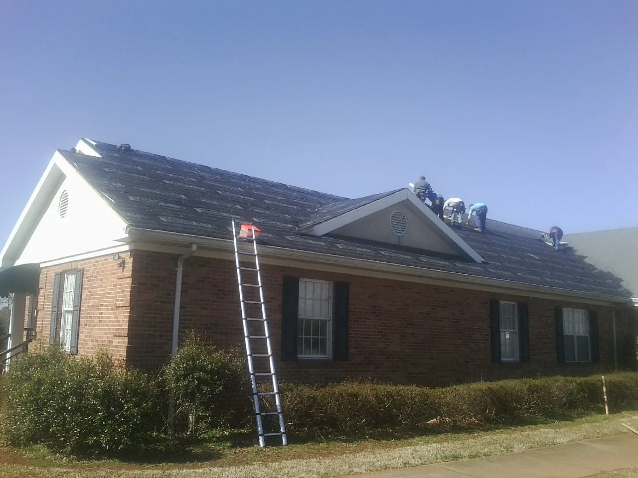 Crew tearing shingles off a brick ranch roof with a ladder set — Metal Roof Repair work by our crew in Old Orchard Beach