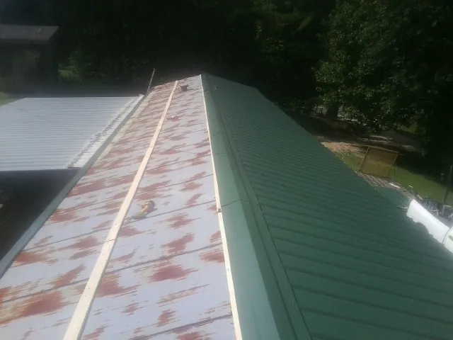 Old rusted panels beside newly installed green metal roofing — Wind Damage Roof Repair by Roofing Brothers in Old Orchard Beach