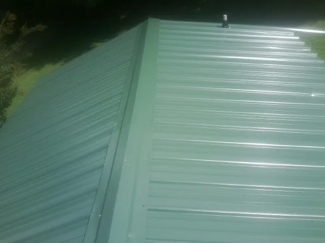 New green metal panels meeting at the ridge of a roof — Flat Roof Repair work by our crew in Old Orchard Beach