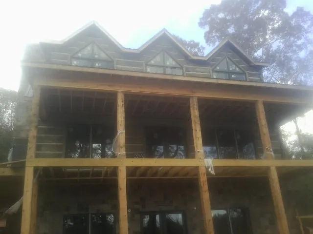 Dormers and porch framing on a large log home under construction — Roof Coating work by our crew in Old Orchard Beach