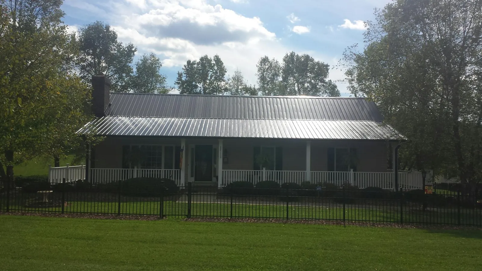 Gray metal roof on a brick ranch with a full width front porch — Gutter Guard Installation work by our crew in Old Orchard Beach