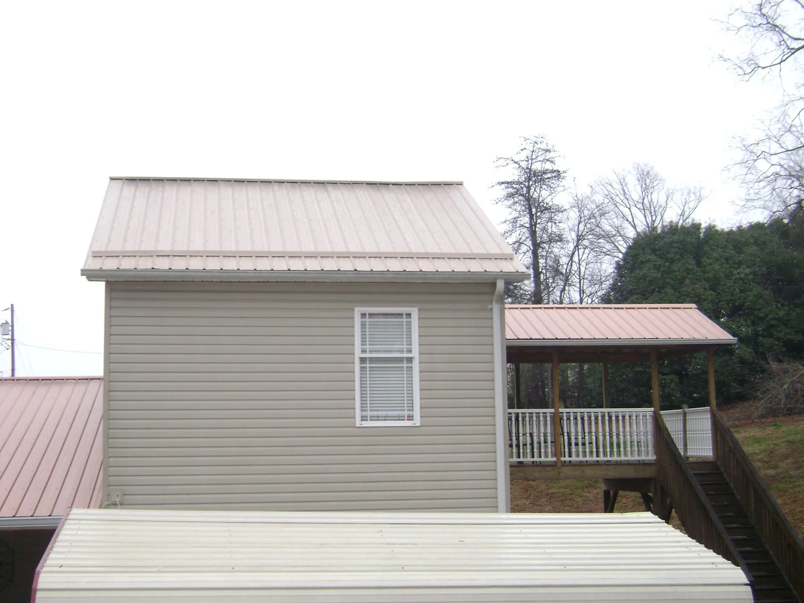 Tan metal roofs on a two story addition and attached porch, from a Roof Replacement job in Old Orchard Beach