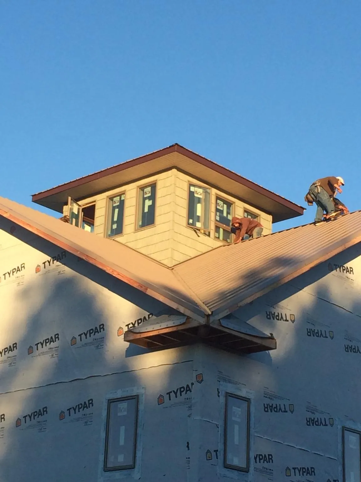 Roofers working around a rooftop cupola on a new metal roof at sunset — Roof Waterproofing in Old Orchard Beach by Roofing Brothers